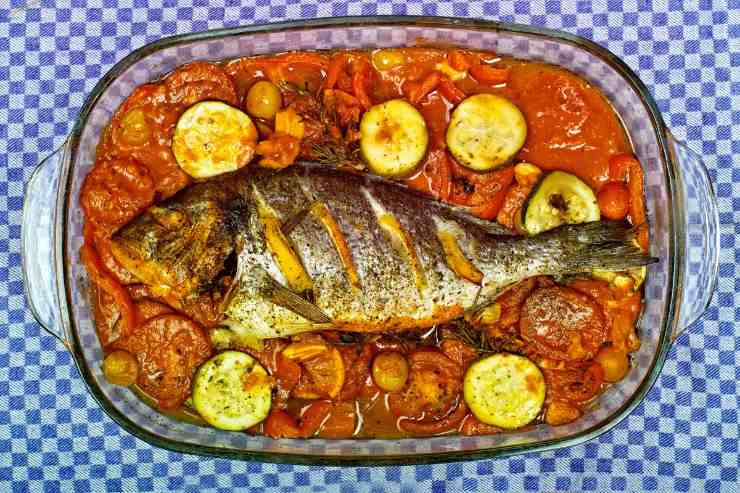 orata intera con pomodorini, olive e zucchine