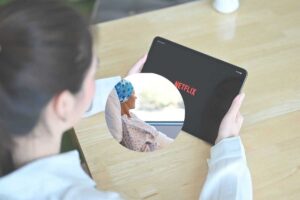 una ragazza guarda netflix sul tablet e nel cerchietto una donna col cancro