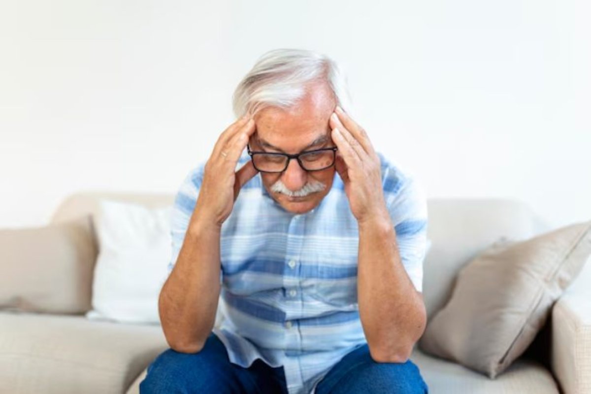 uomo seduto sul divano triste con le mani sulle tempie
