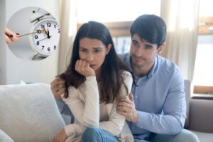 marito e moglie preoccupati e sullo sfondo una sveglia