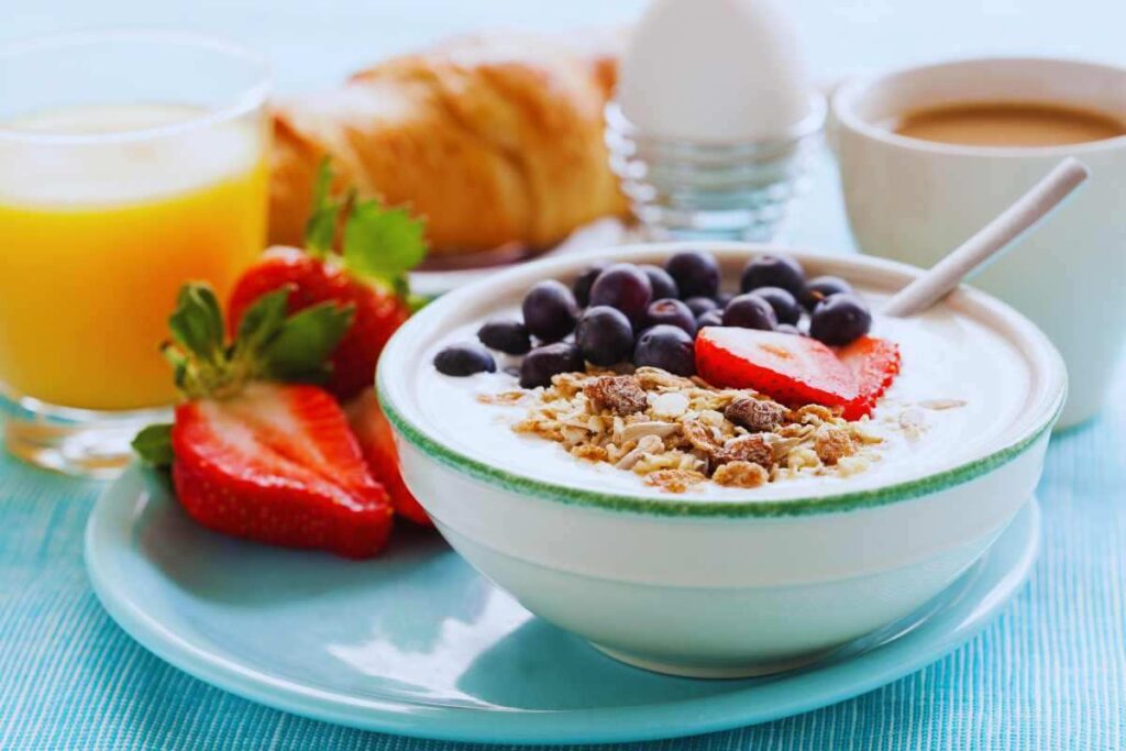 Una tazza di latte con la frutta delle uova e dei dolci