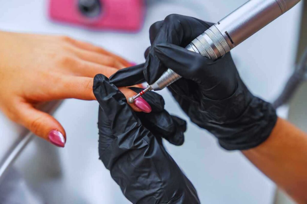 Mani di estetista che lavorano le mani di una cliente